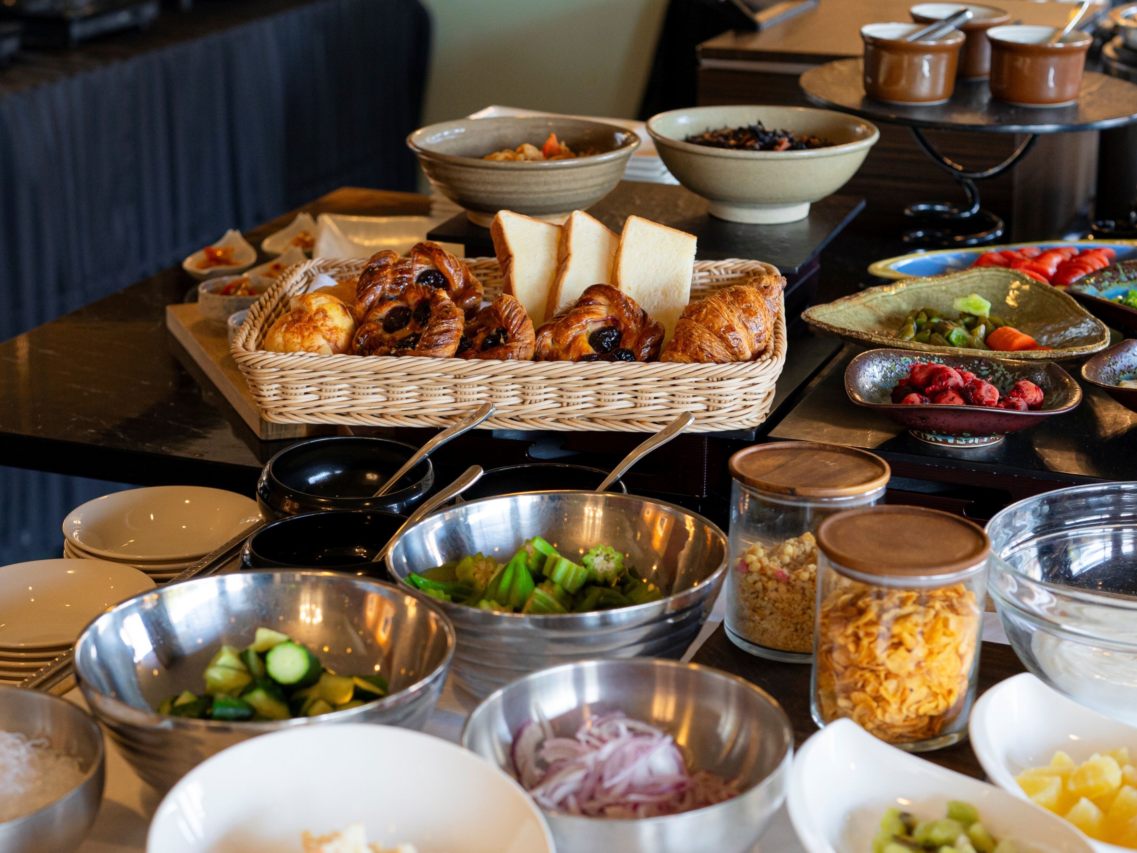 Une table de buffet proposant divers plats, notamment du pain, des salades et des fruits.
