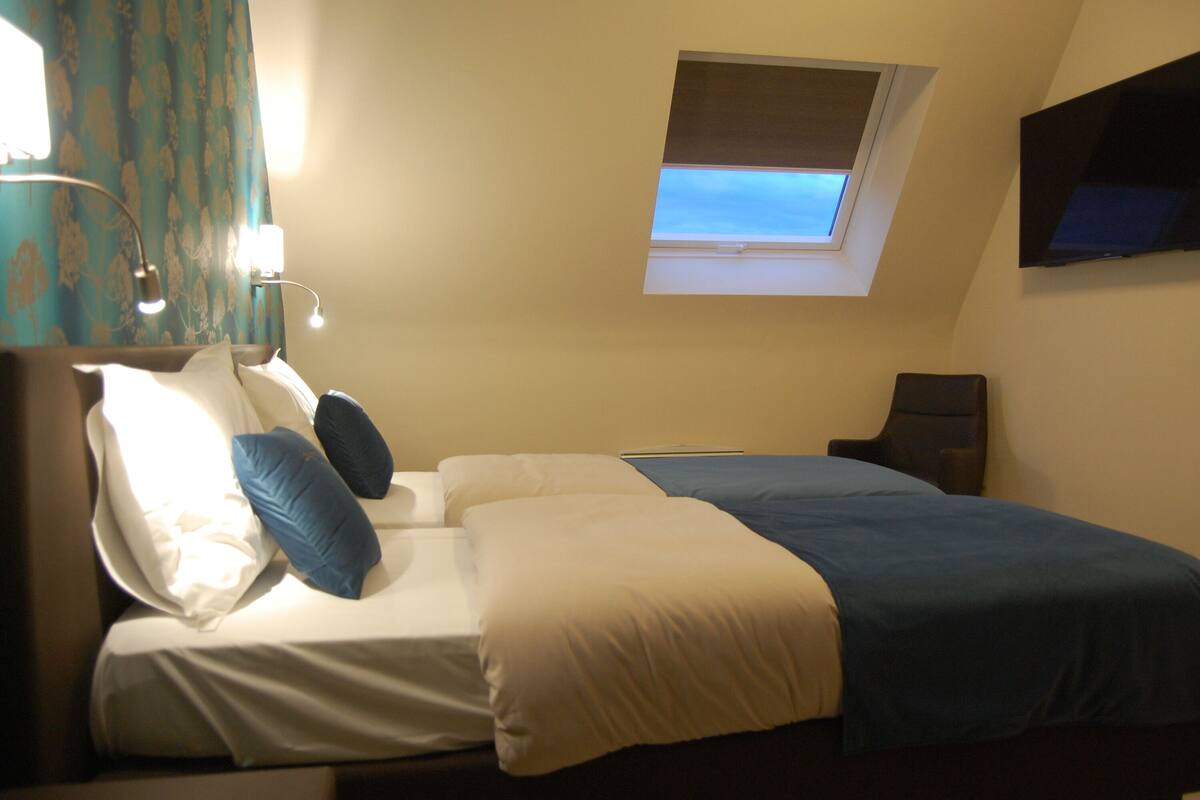Een hotelkamer met een bed, een bureau, een stoel, een televisie en een raam met uitzicht.