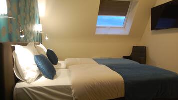 Une chambre d’hôtel avec un lit, un bureau, une chaise, une télévision et une fenêtre donnant sur un paysage agréable.