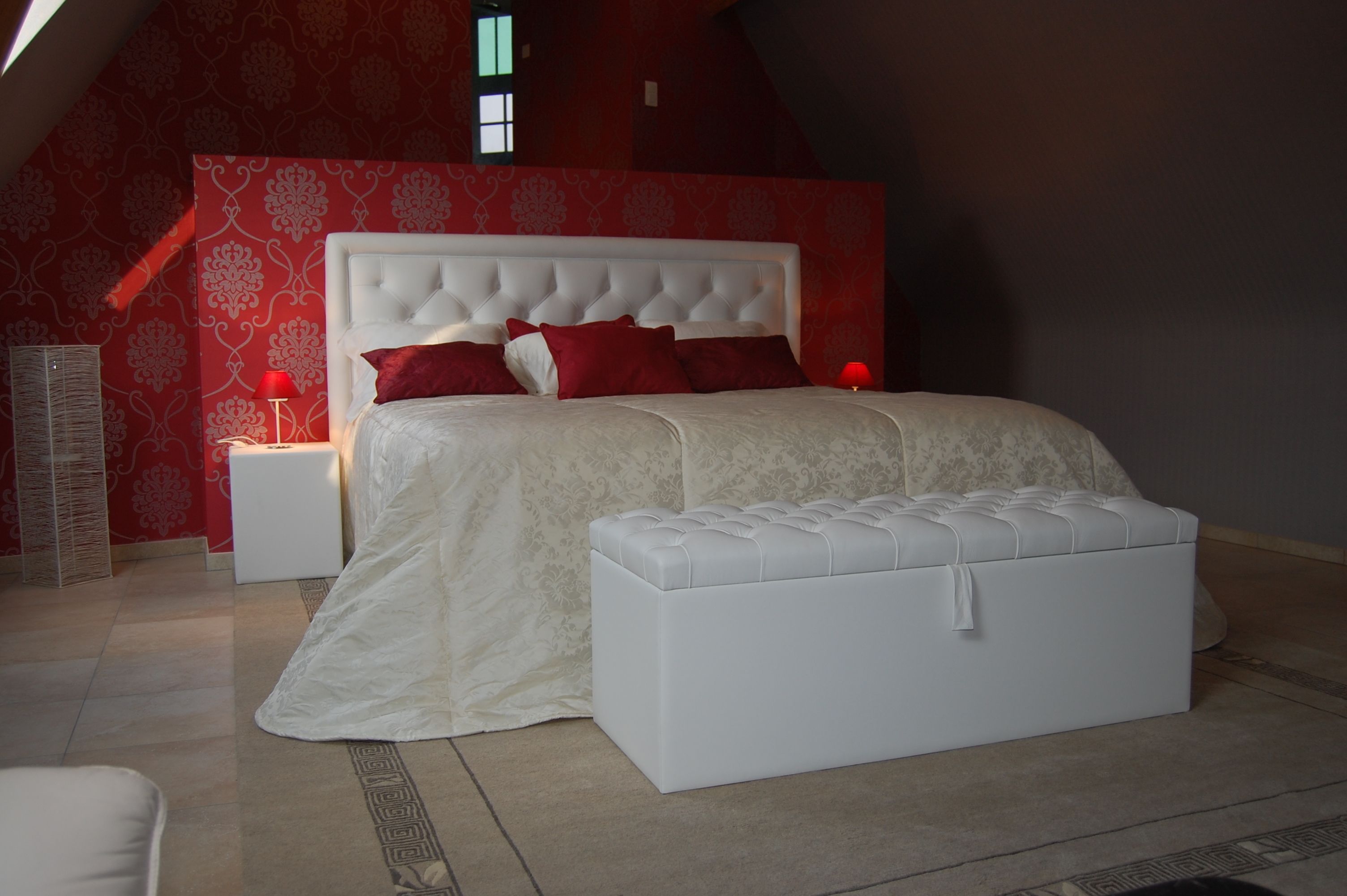 Un dormitorio con una cama grande, un cabecero blanco y una pared de acento roja.