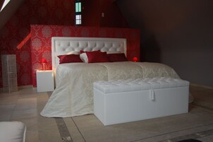 Un dormitorio con una cama grande, un cabecero blanco y una pared de acento roja.