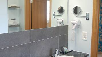 A bathroom with a marble sink, a mirror, a hairdryer, and a towel rack.