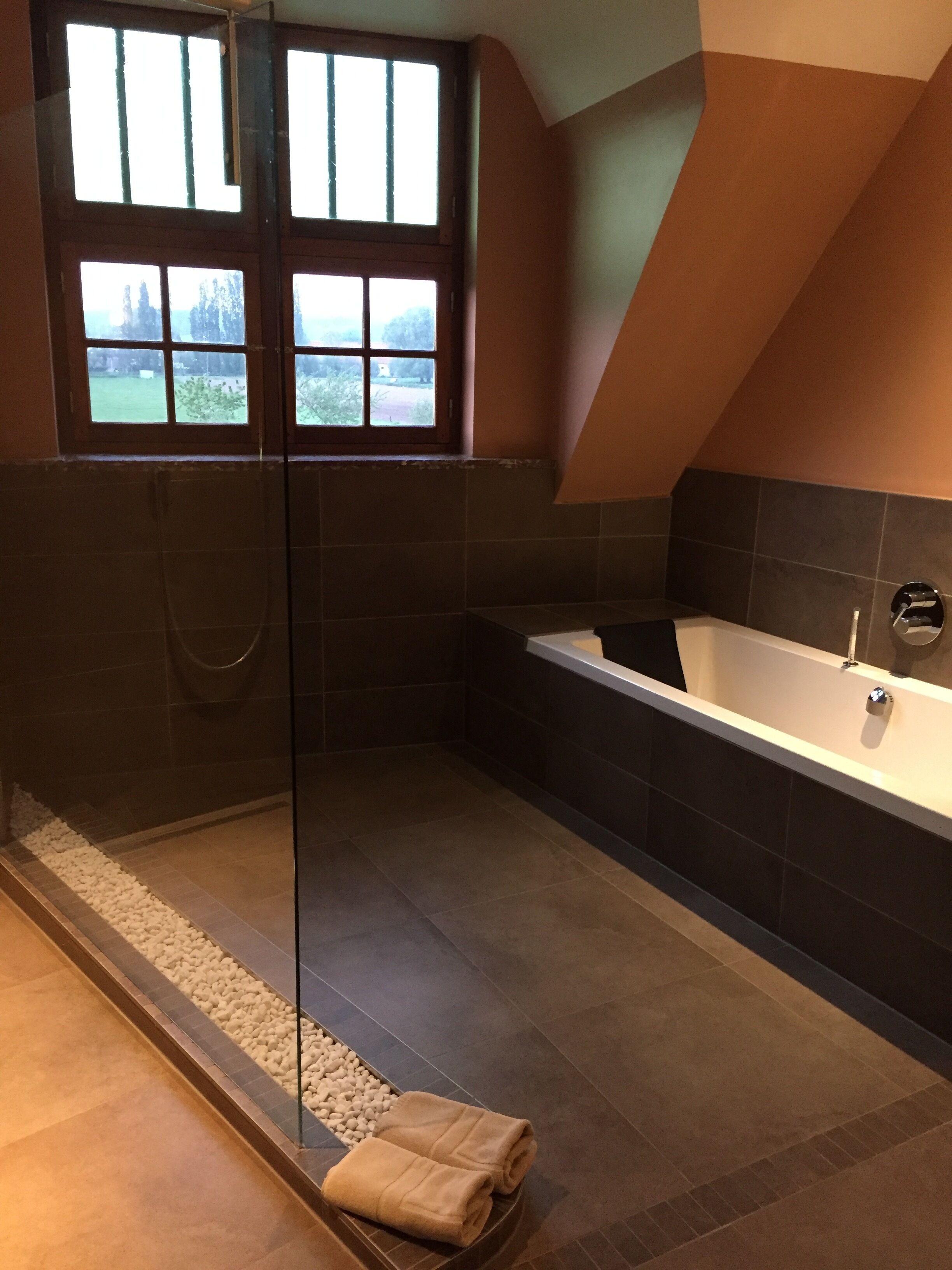 Une salle de bain moderne avec une douche à parois de verre, une baignoire et une vue par les fenêtres.