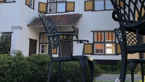Un edificio con diverse finestre e un giardino con sedie e due conigli.