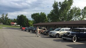A parking lot with several vintage cars parked in front of a building.