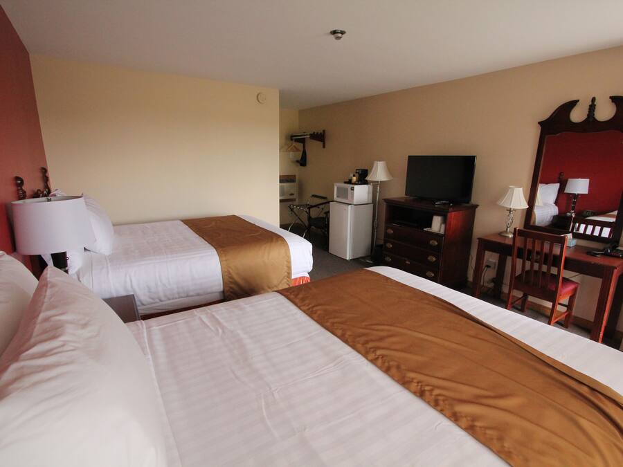 Een hotelkamer met twee bedden, een bureau, een televisie en een spiegel.