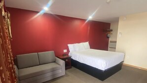 A bedroom with a bed, a sofa, and a nightstand.