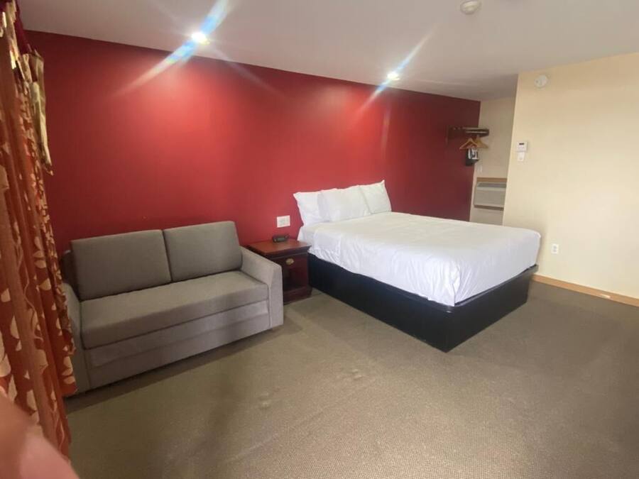 A bedroom with a bed, a sofa, and a nightstand.