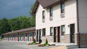 A motel with multiple rooms, a parking lot, and a row of colorful chairs outside.