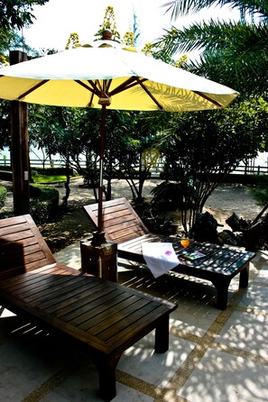 Una piscina al aire libre, sombrillas, sillones reclinables de piscina