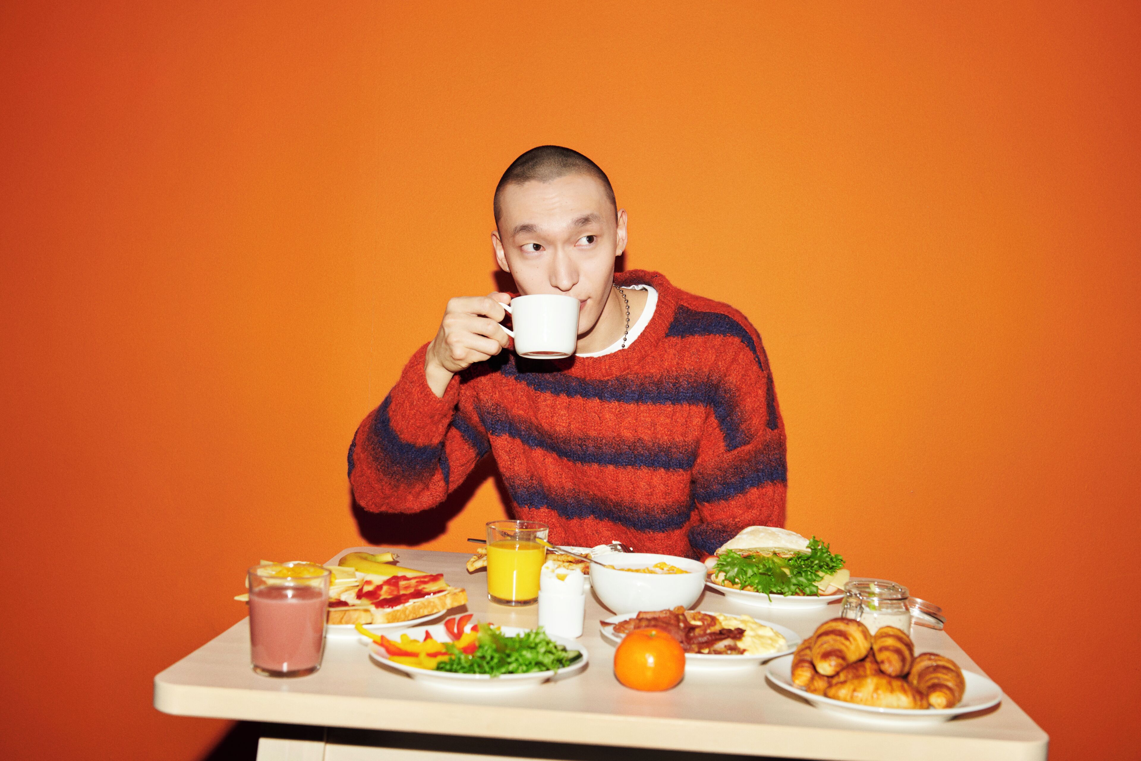 A person sitting at a table with various breakfast items including toast, eggs, and pastries.