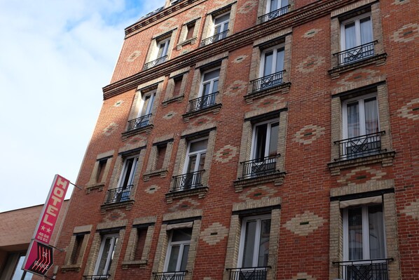 Un edificio de ladrillo rojo con varias ventanas y balcones. Un letrero indica que es un hotel.