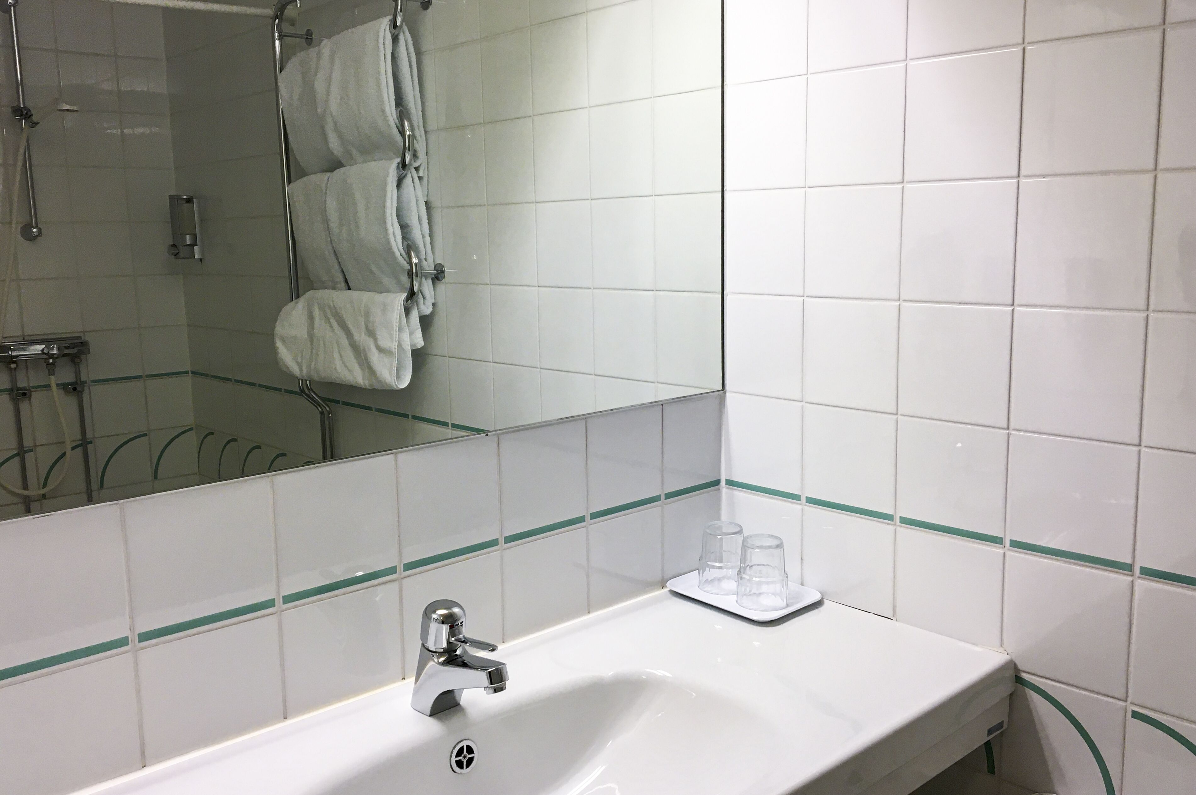 Un baño con lavabo, espejo y toallero.