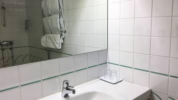Un baño con lavabo, espejo y toallero.