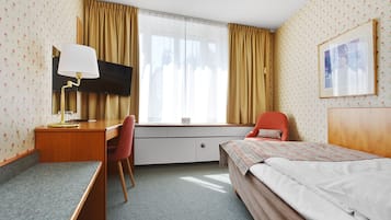 Una habitación de hotel con cama, escritorio, silla y televisor.