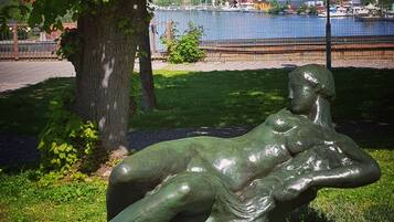 A sculpture of a reclining figure in a park setting with a body of water and buildings in the background.