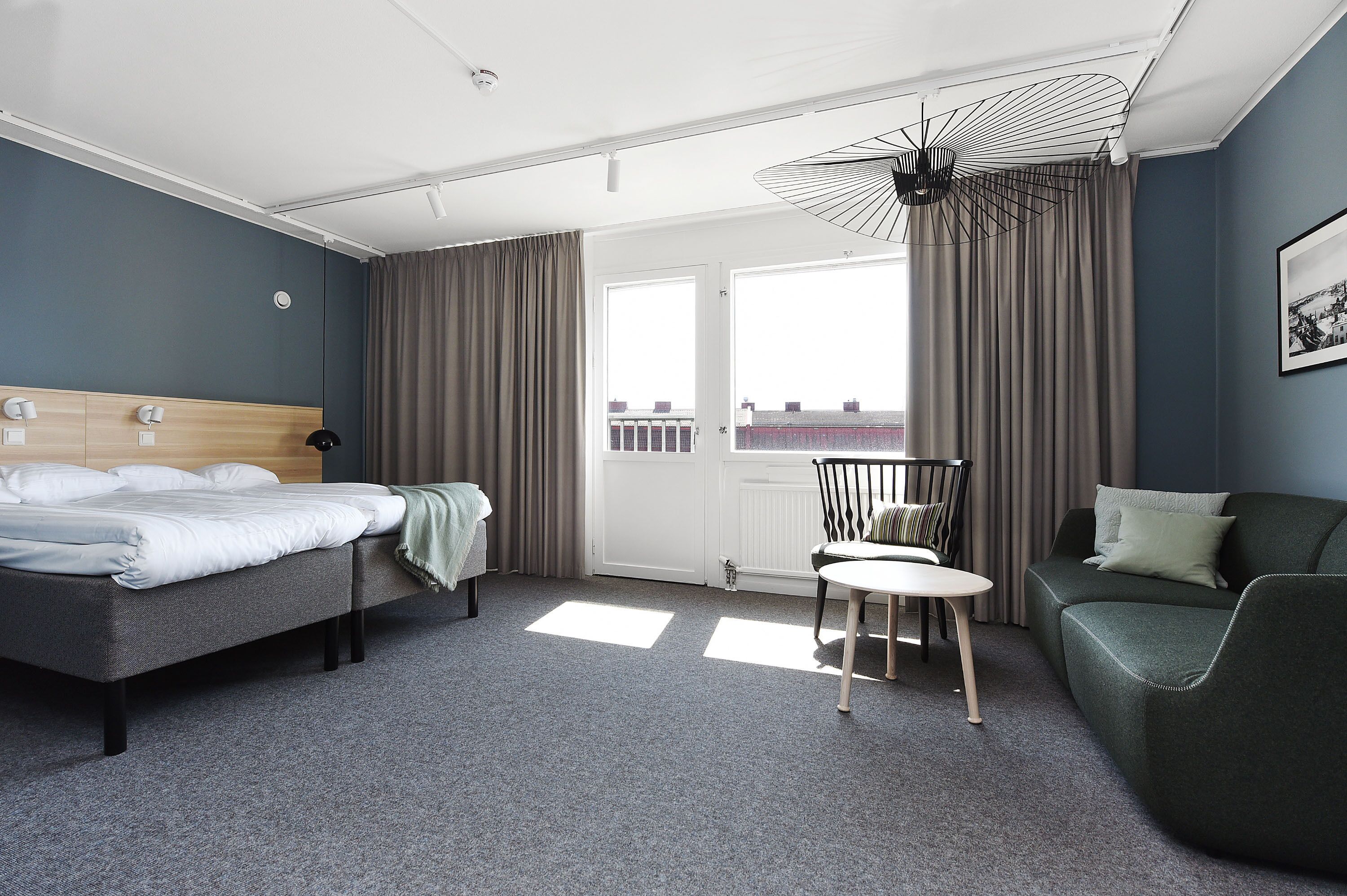 Habitación de hotel con cama, sofá, sillón y mesa.