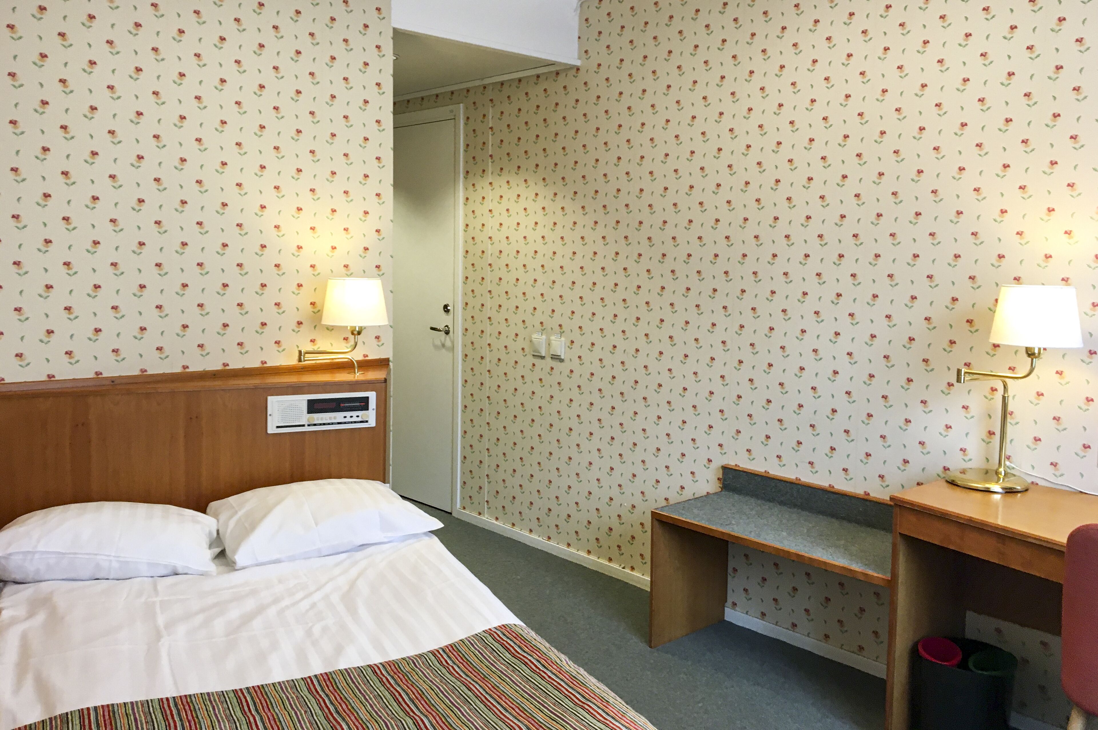Una habitación de hotel con cama, lámparas de noche, escritorio y una silla.