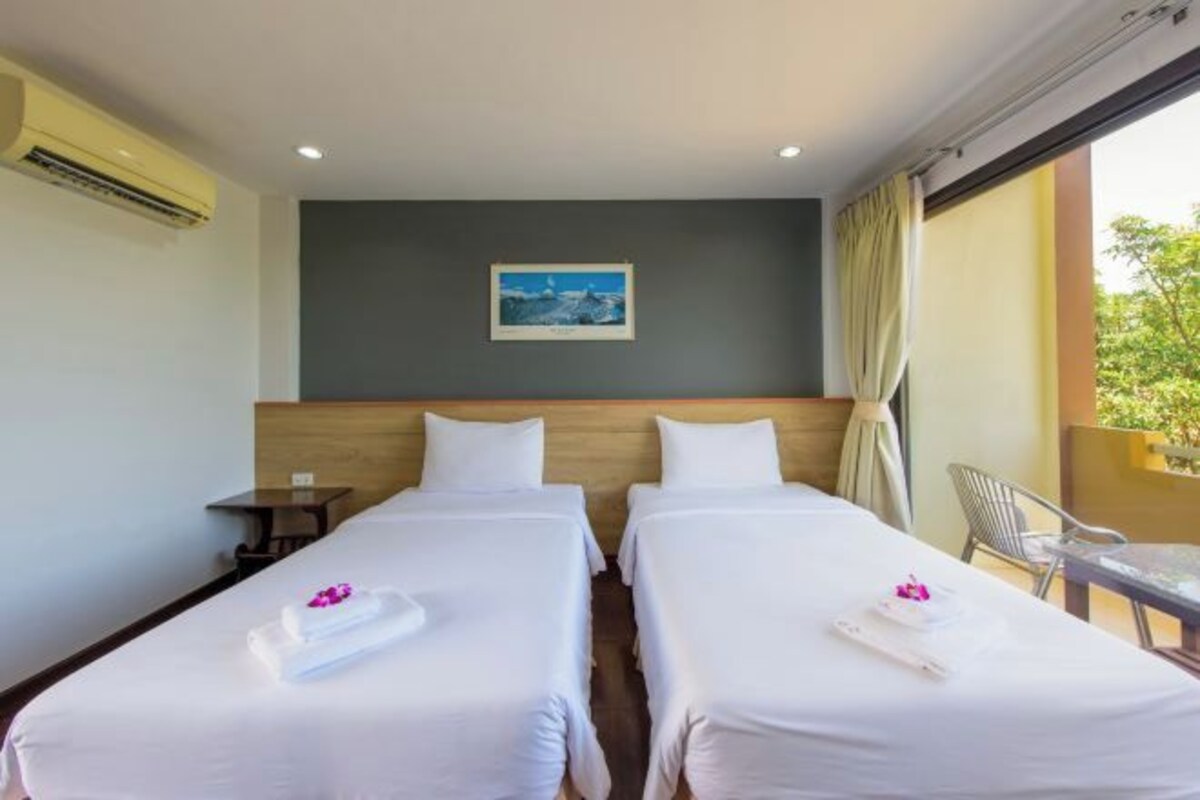 Une chambre d’hôtel avec deux lits, une petite table, une chaise et un balcon avec vue.
