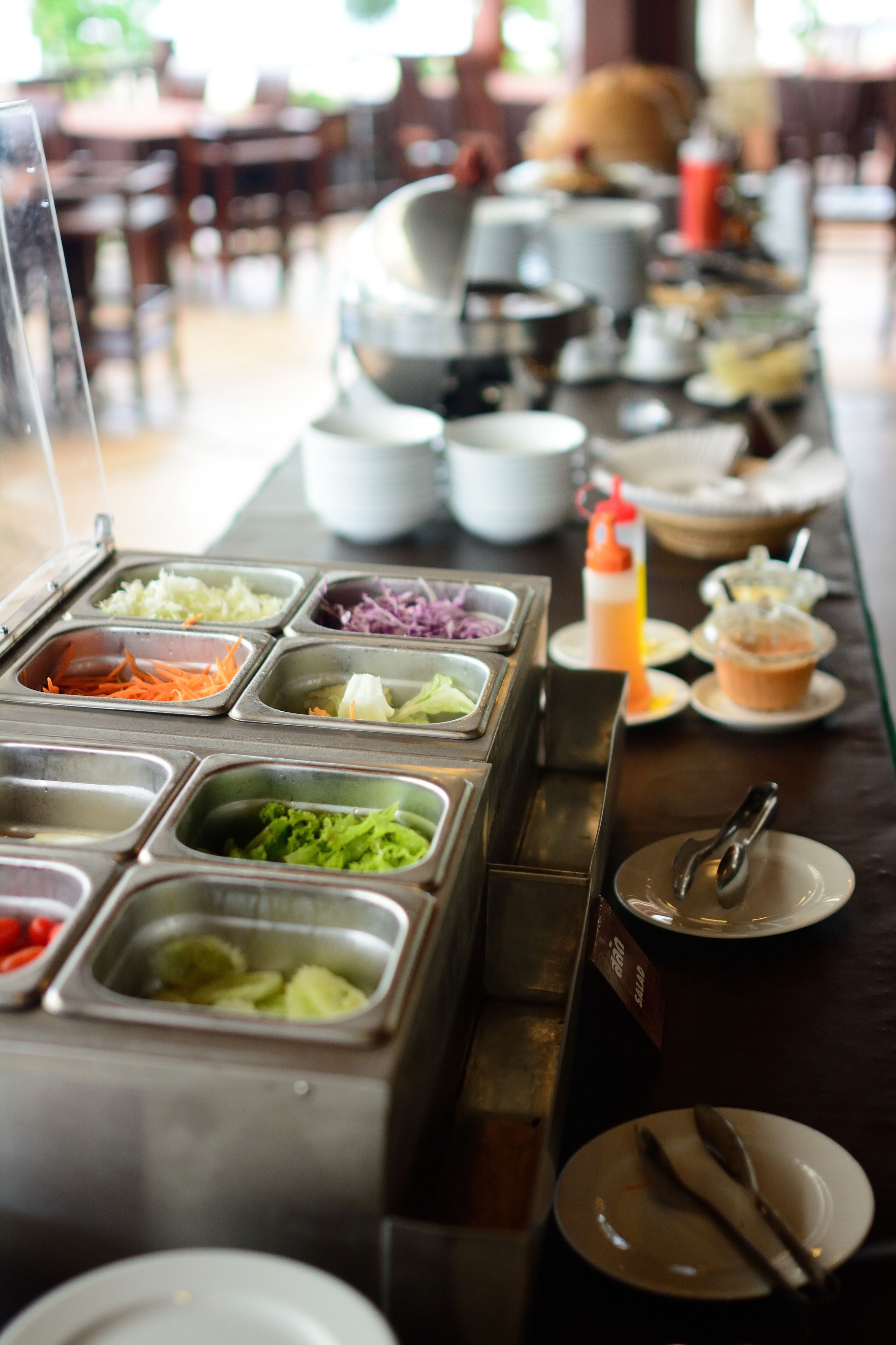 Una barra de buffet con diversas opciones de comida en recipientes metálicos.