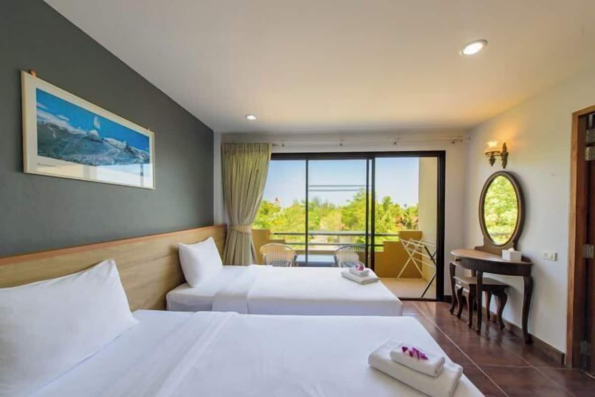 Une chambre d’hôtel avec deux lits, un balcon avec vue, un tableau au mur et un bureau avec un miroir.