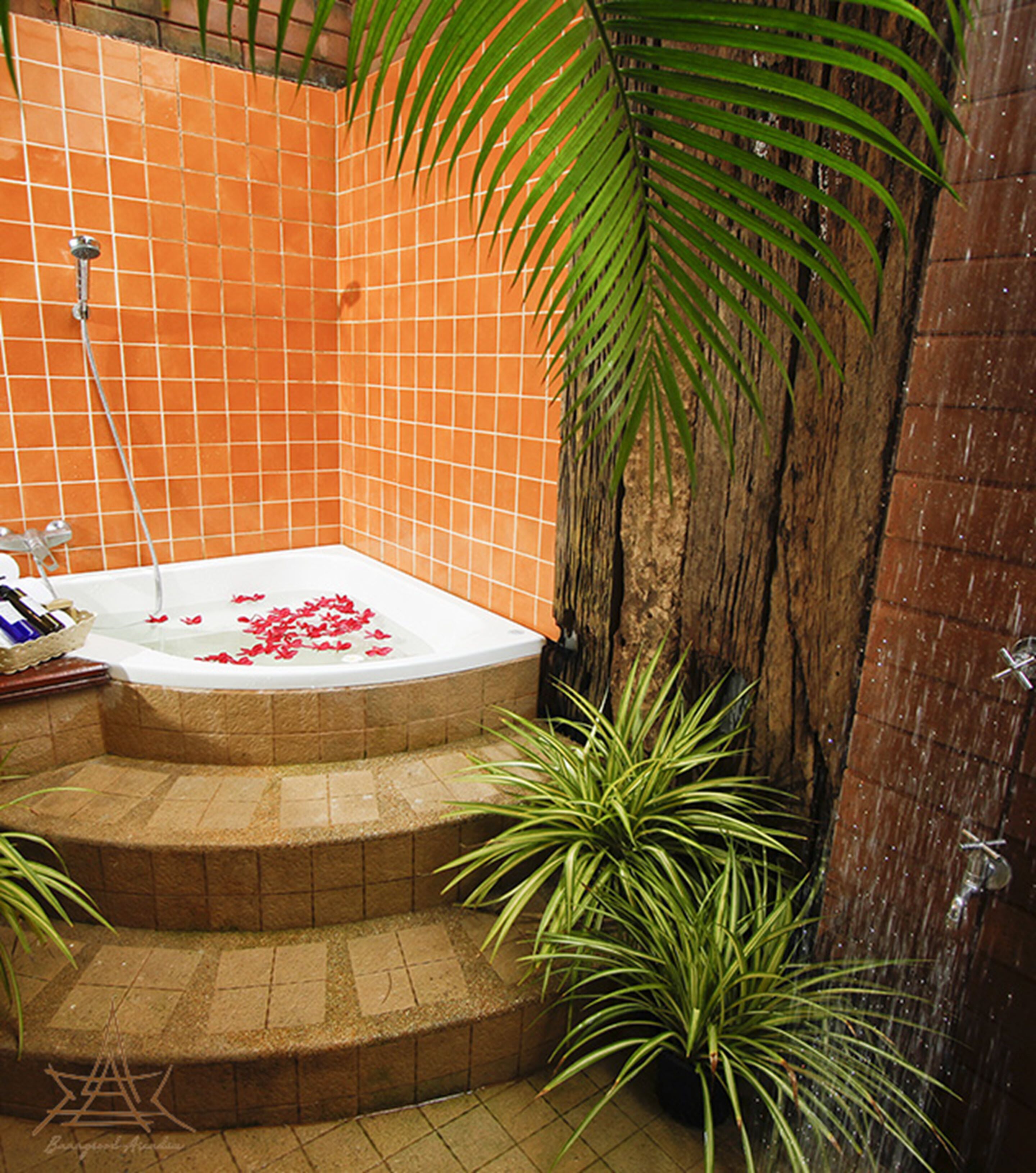 A bathroom with a bathtub, a shower, and a tiled wall. There are plants around the bathtub.