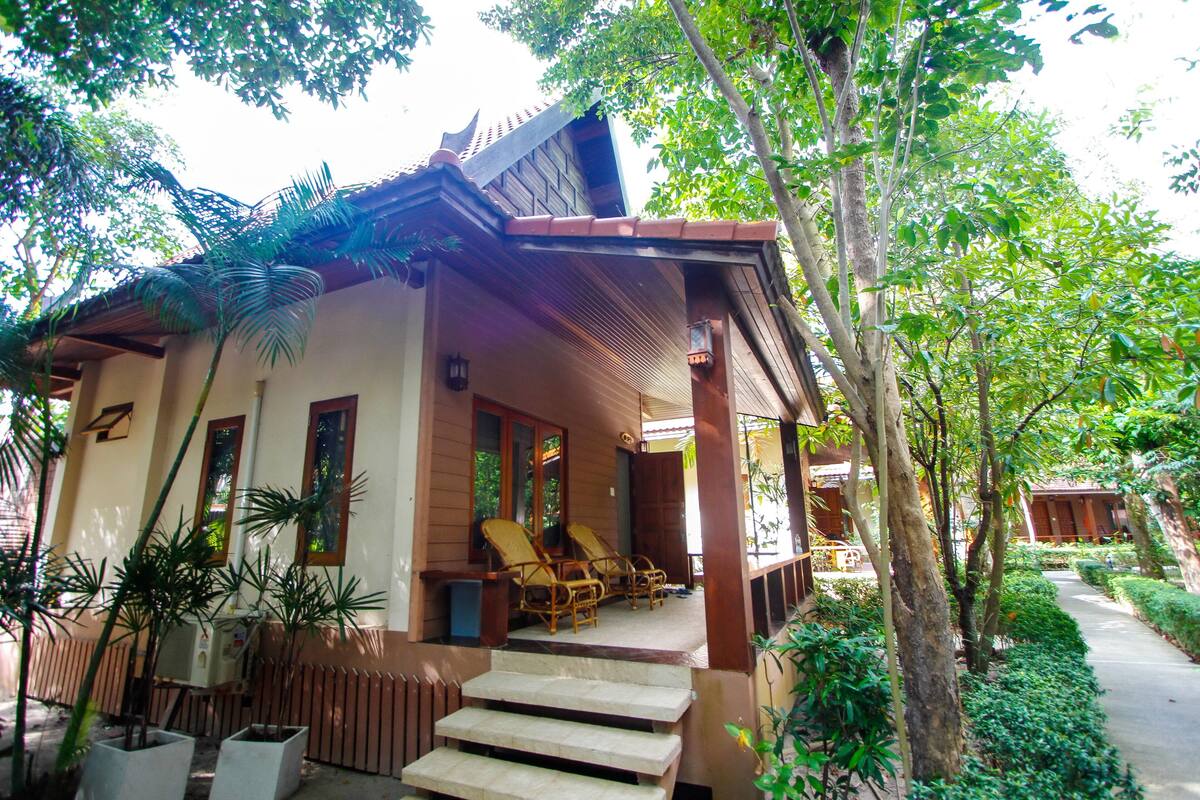 Une maison traditionnelle avec un porche, des marches et des plantes en pot.