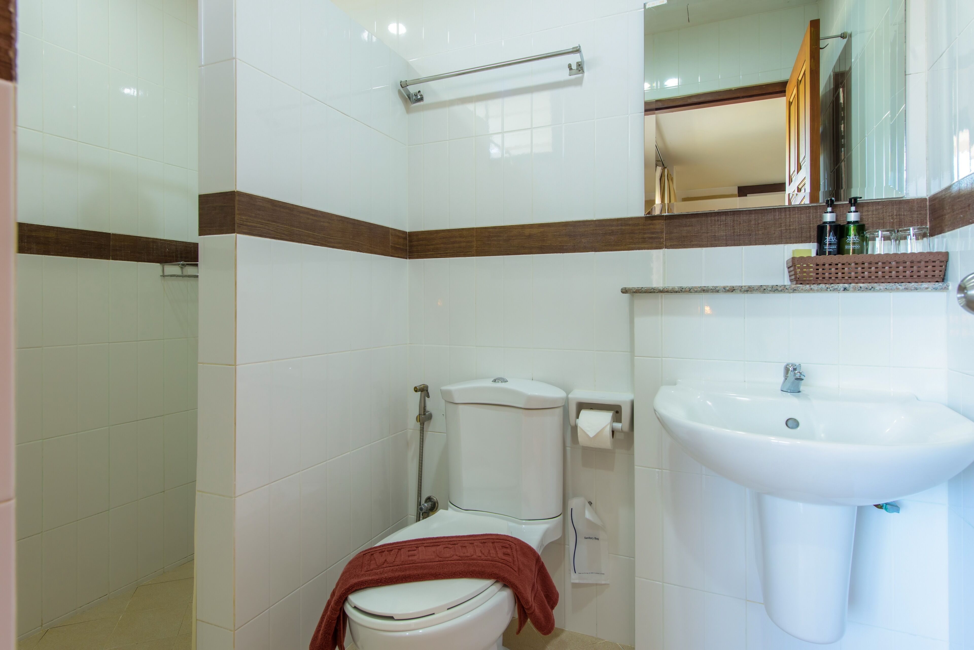 A bathroom with a toilet, sink, and mirror.