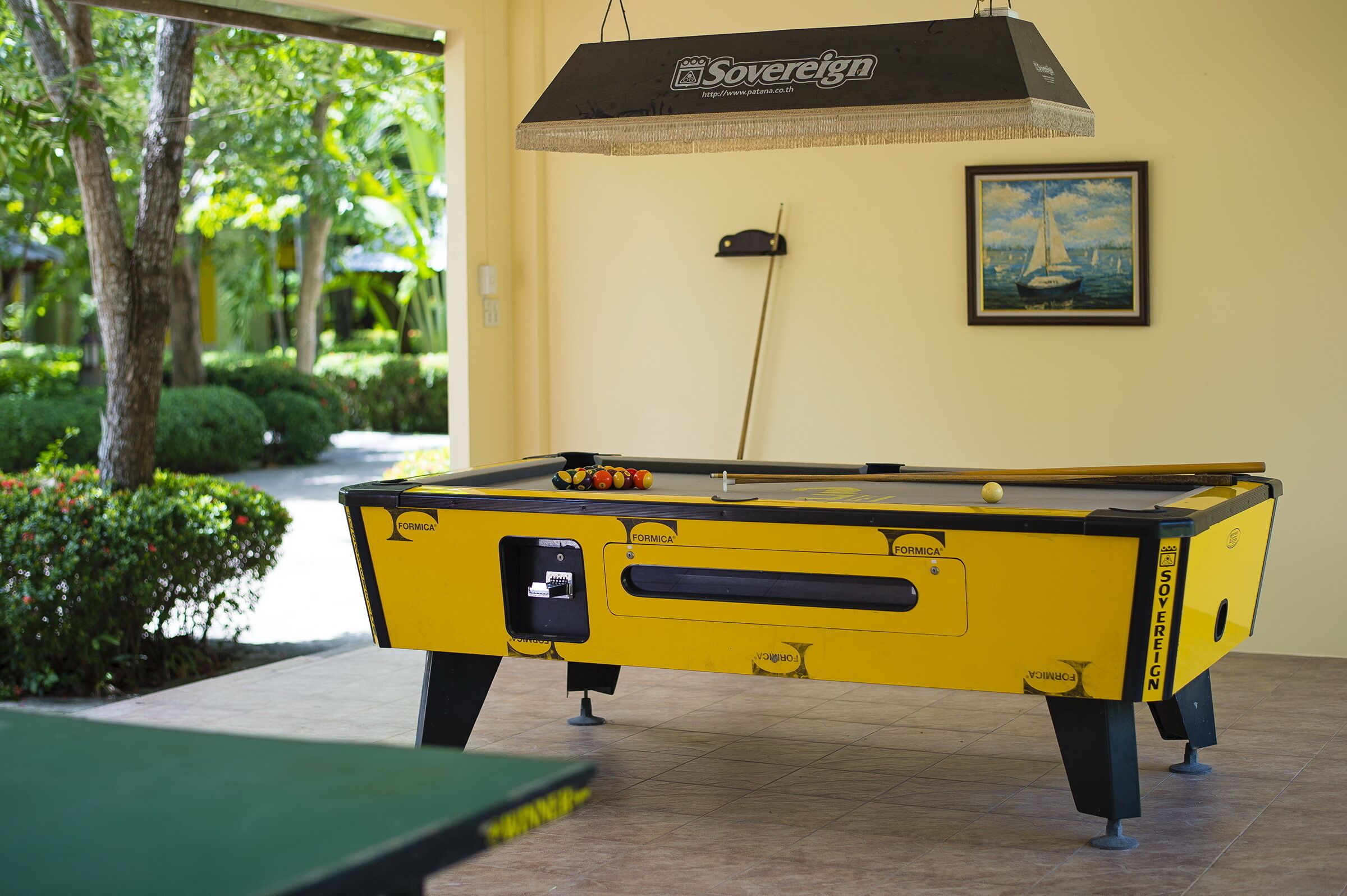 Una mesa de billar con diseño amarillo y negro, una taco de pool y un cuadro en la pared.