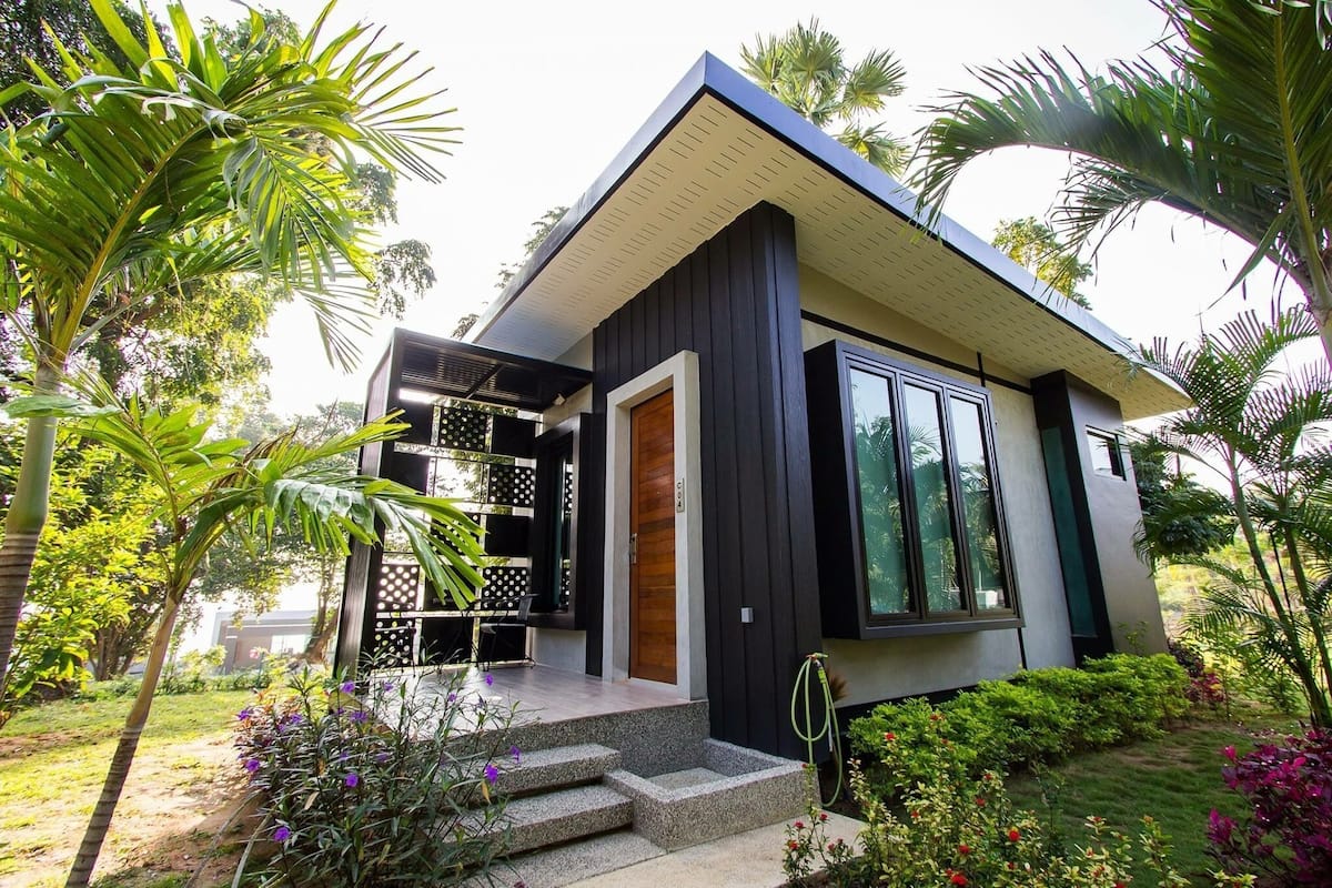 A modern house with a dark exterior, large windows, and a wooden door.