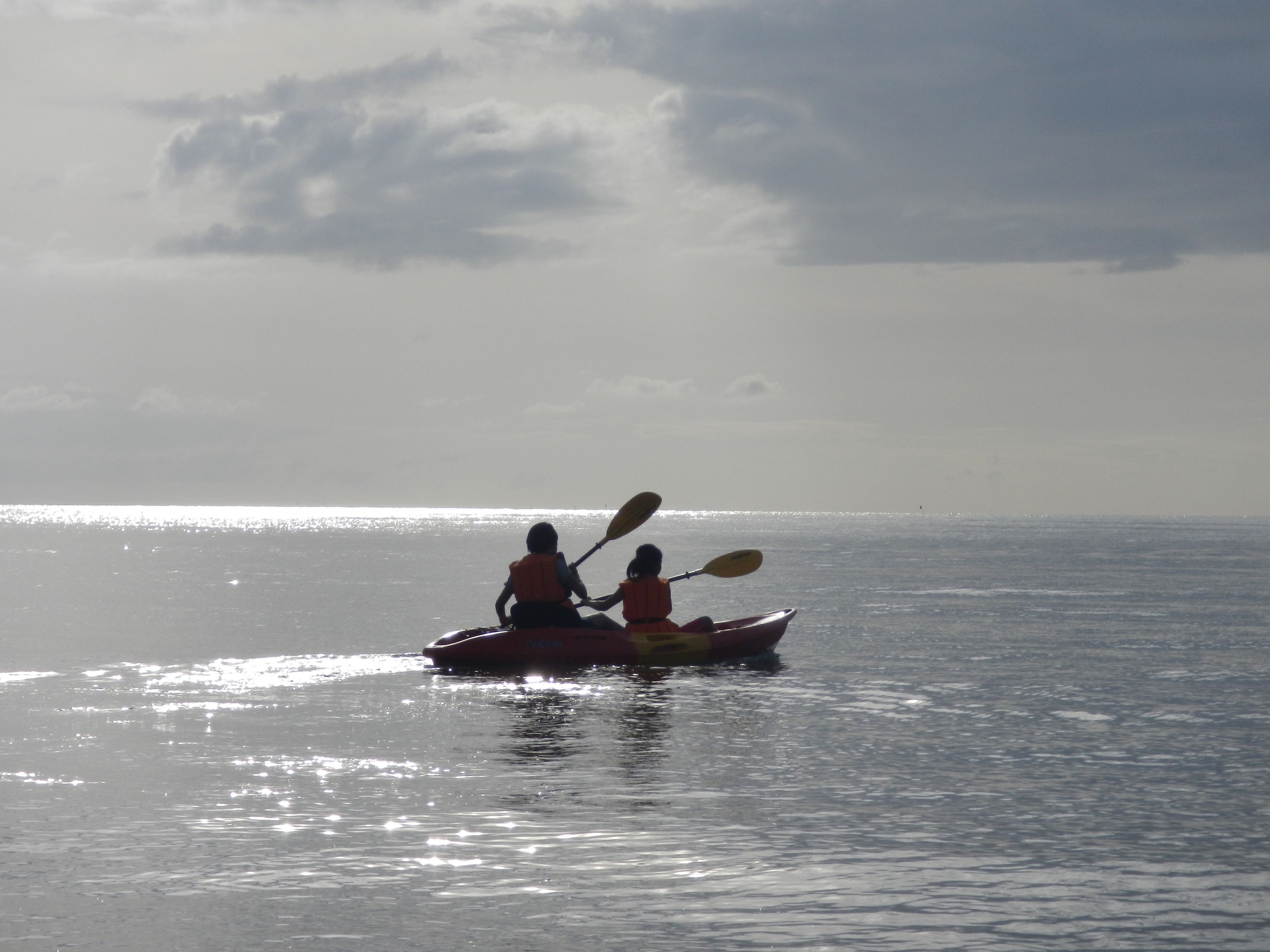 Una canoa con dos personas en un mar tranquilo.