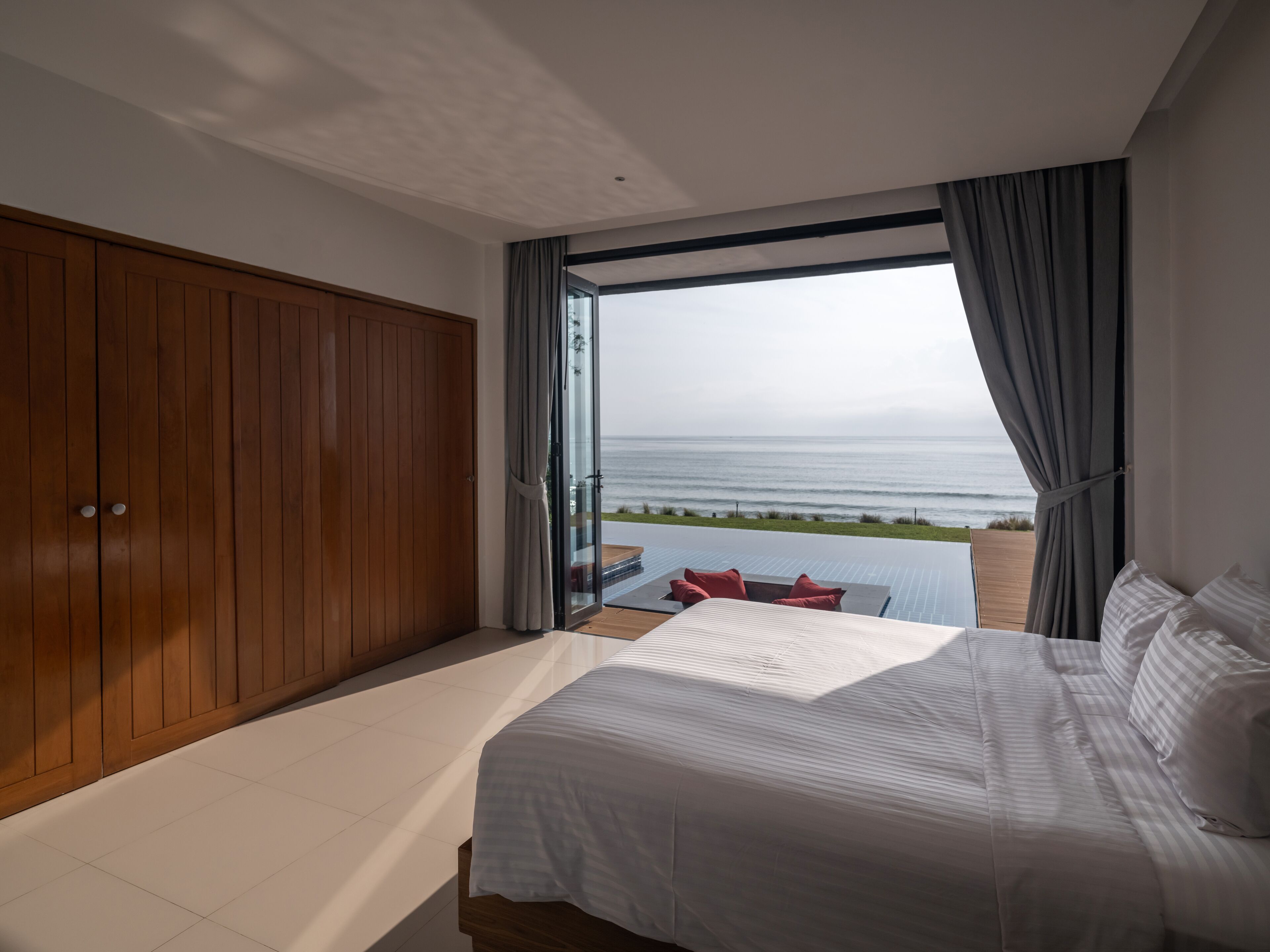 Une chambre avec un grand lit, une armoire en bois et une vue sur la mer.