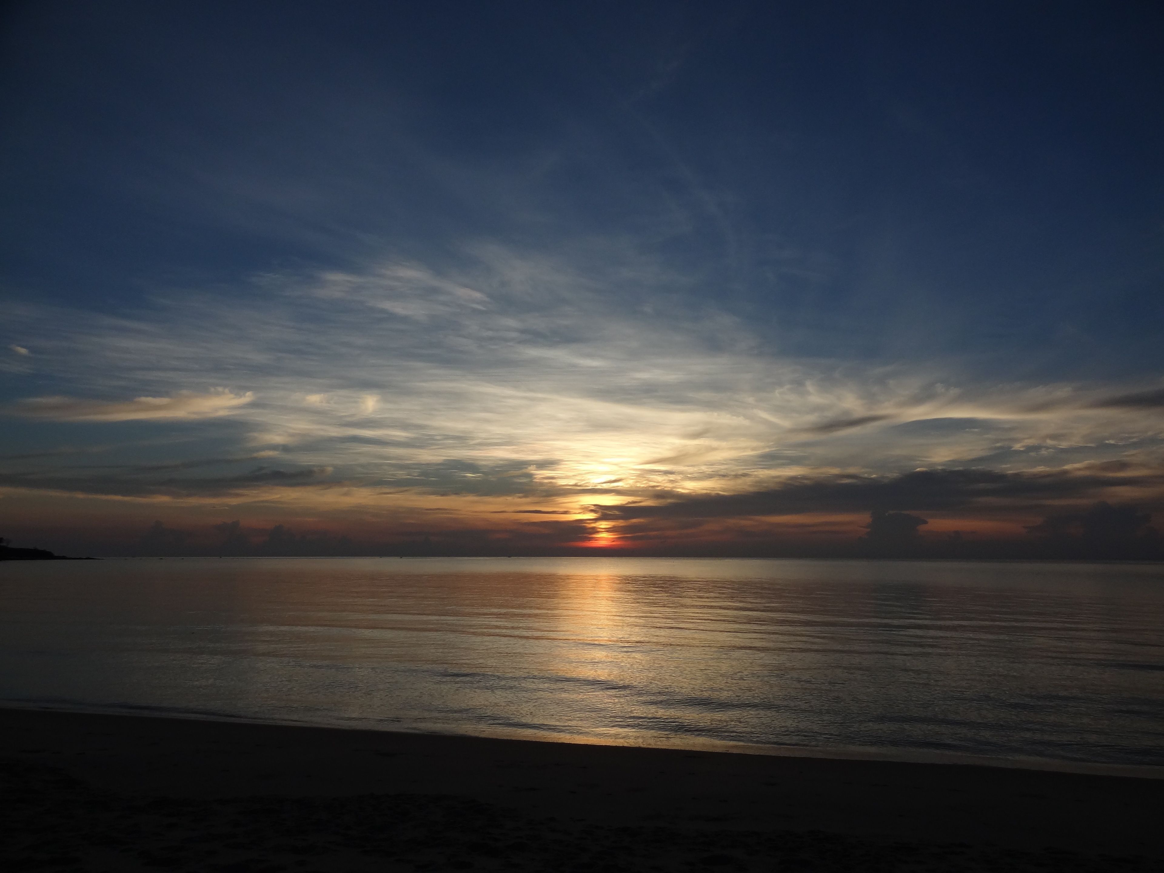A sunset over a calm sea with a clear sky.
