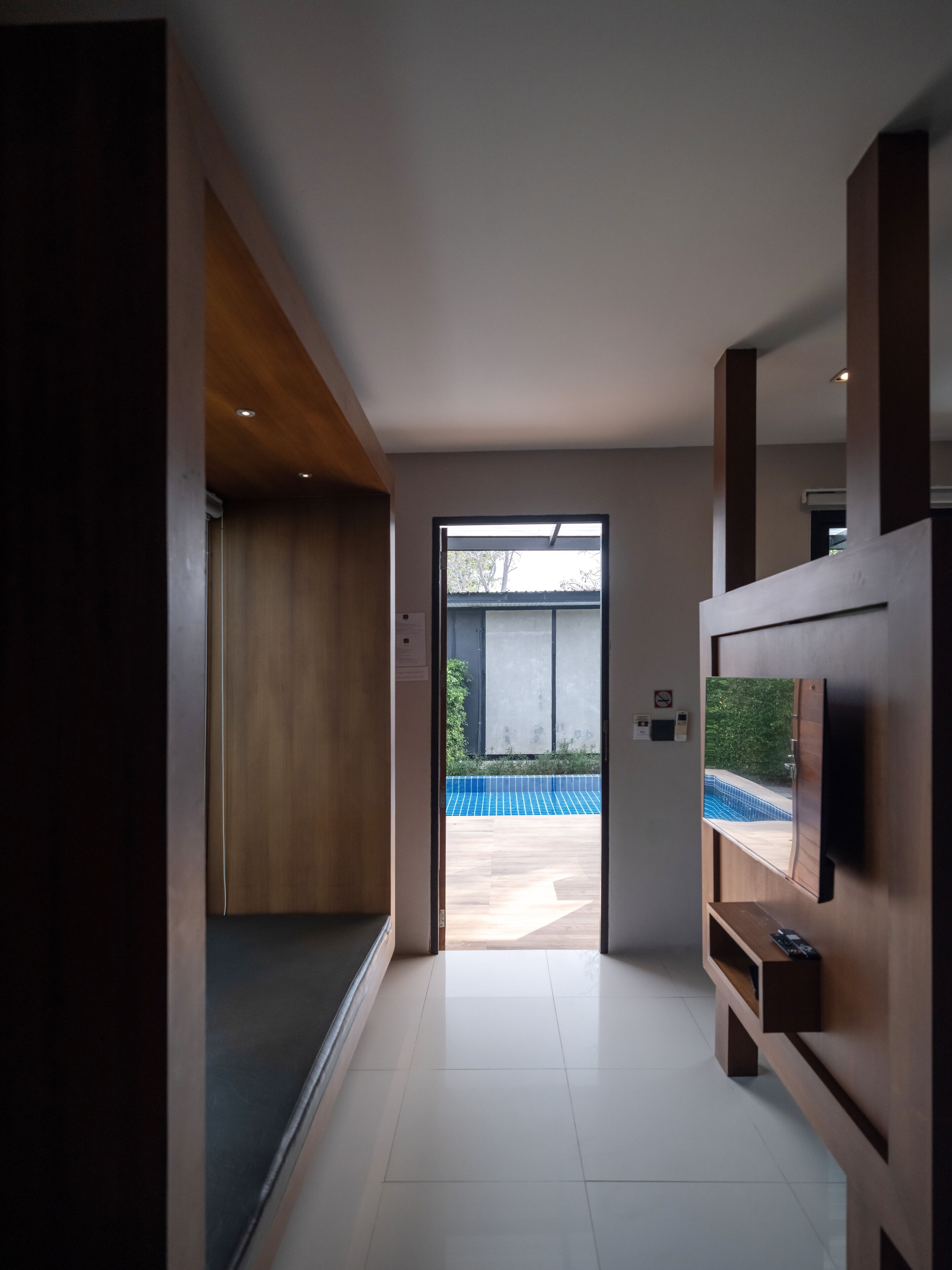 Ein modernes Interieur mit Holzboden, einer Tür zu einem Außenbereich und einem Wand-Fernseher.