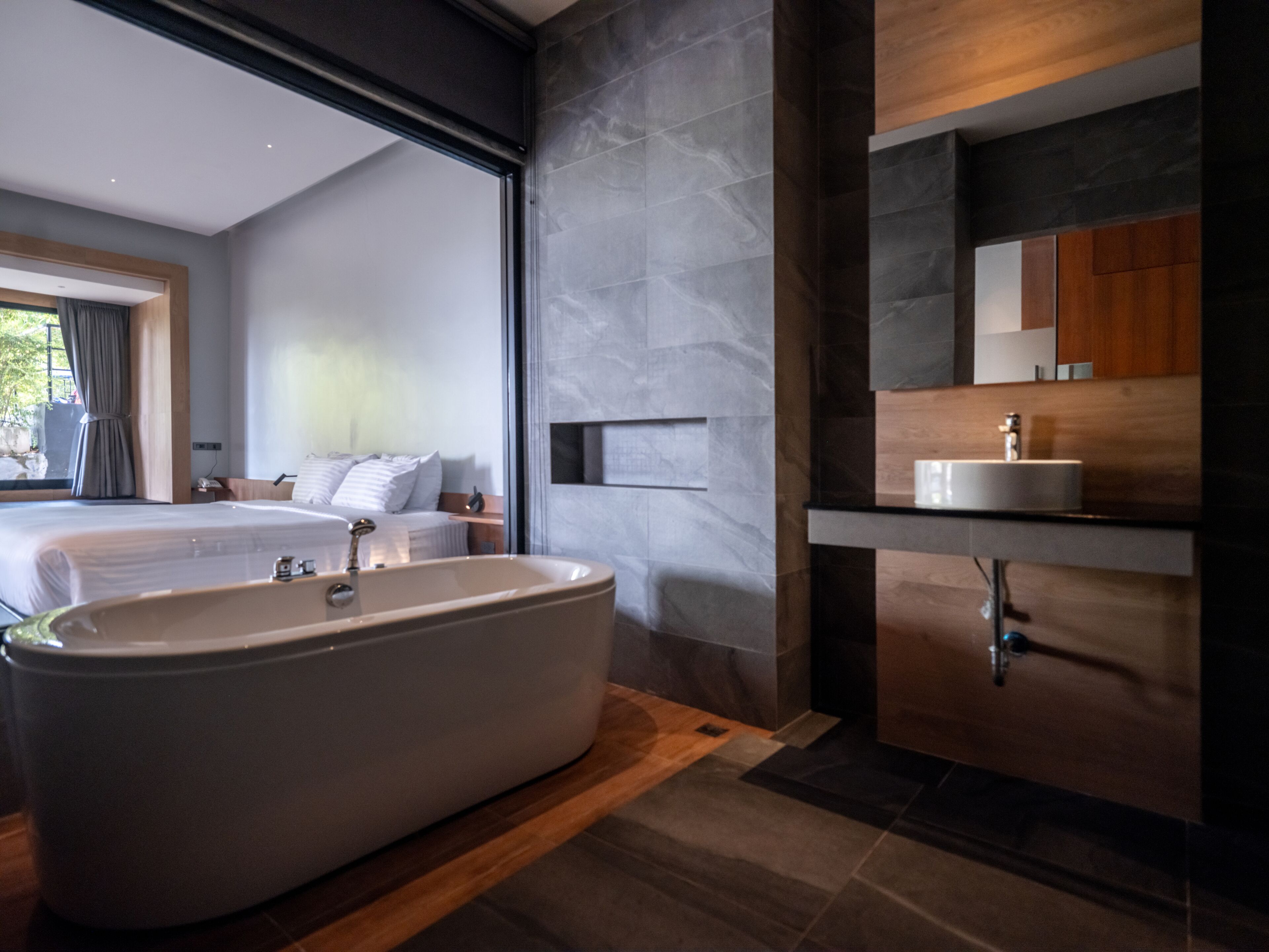 A modern bathroom with a freestanding bathtub, a wooden vanity, and a large mirror.