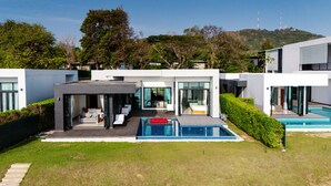 A modern house with a pool, a covered patio, and a view of a hill with trees. - Sunshine Paradise Resort (Thap Sakae)