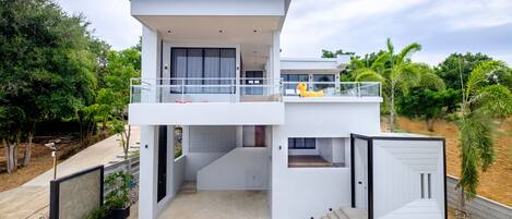 A modern two-story house with a balcony, a staircase, and a garden area.