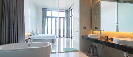 A modern bathroom with a large bathtub, a vanity with two sinks, and a large mirror.