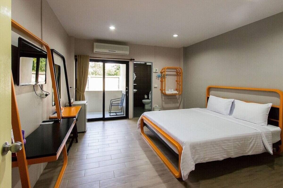 A hotel room with a bed, a desk, a chair, and a bathroom visible through an open door.