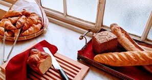 A variety of bread and pastries on a kitchen counter near a window. - L'Hôtel Particulier (Bordeaux)