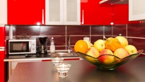 Una cocina con armarios rojos, un microondas y un tazón de fruta sobre la encimera.