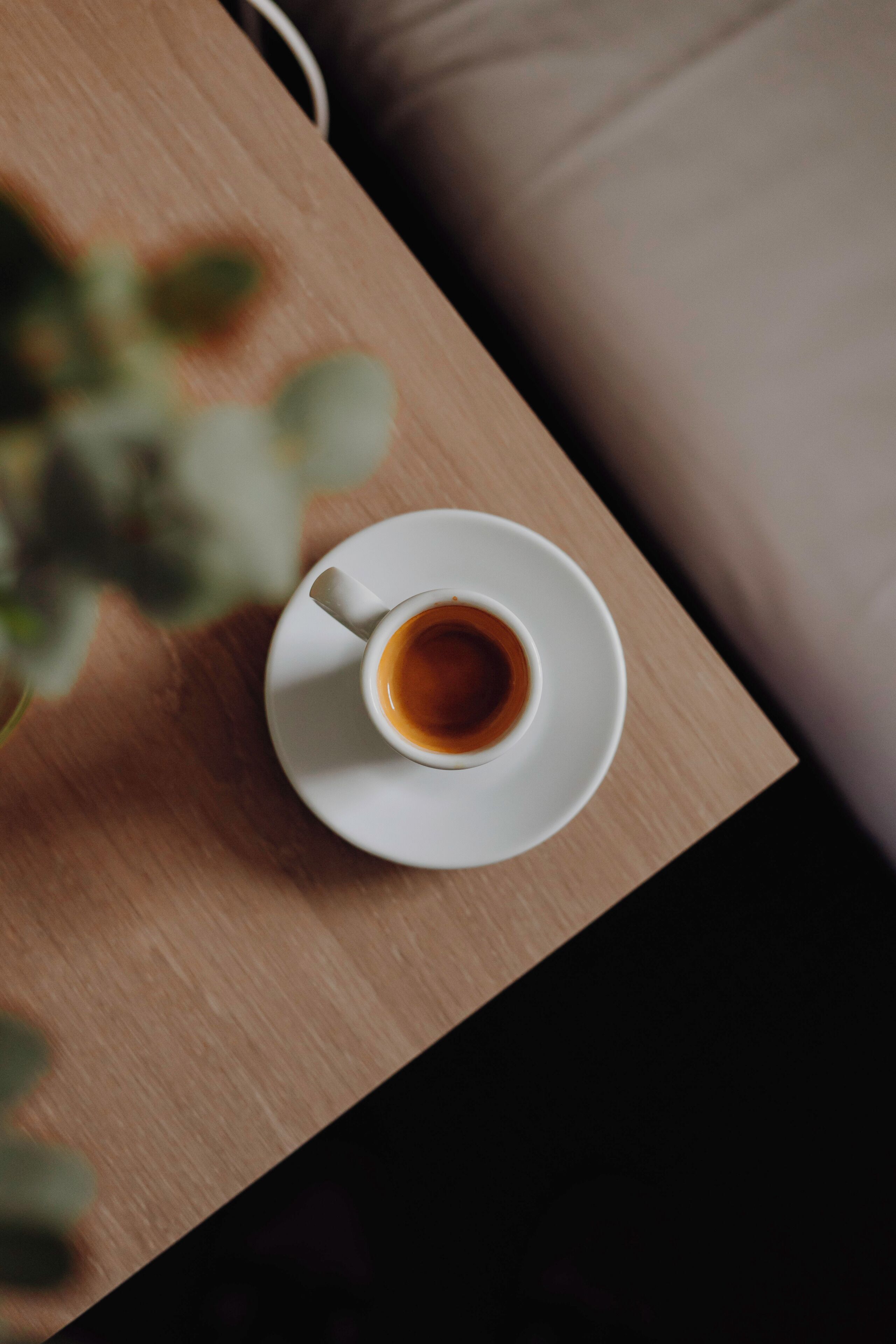 Una taza de café sobre un platito blanco sobre una mesa de madera.