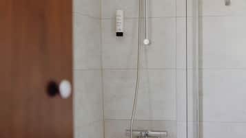 Un baño con una bañera blanca, ducha con cabezal de ducha de mano y un perchero para toallas.