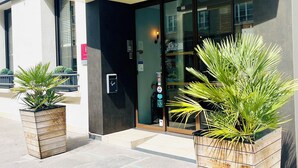 The exterior of a hotel named 'BRISTOL HOTEL' with a modern facade, large glass entrance, and two potted plants in front.