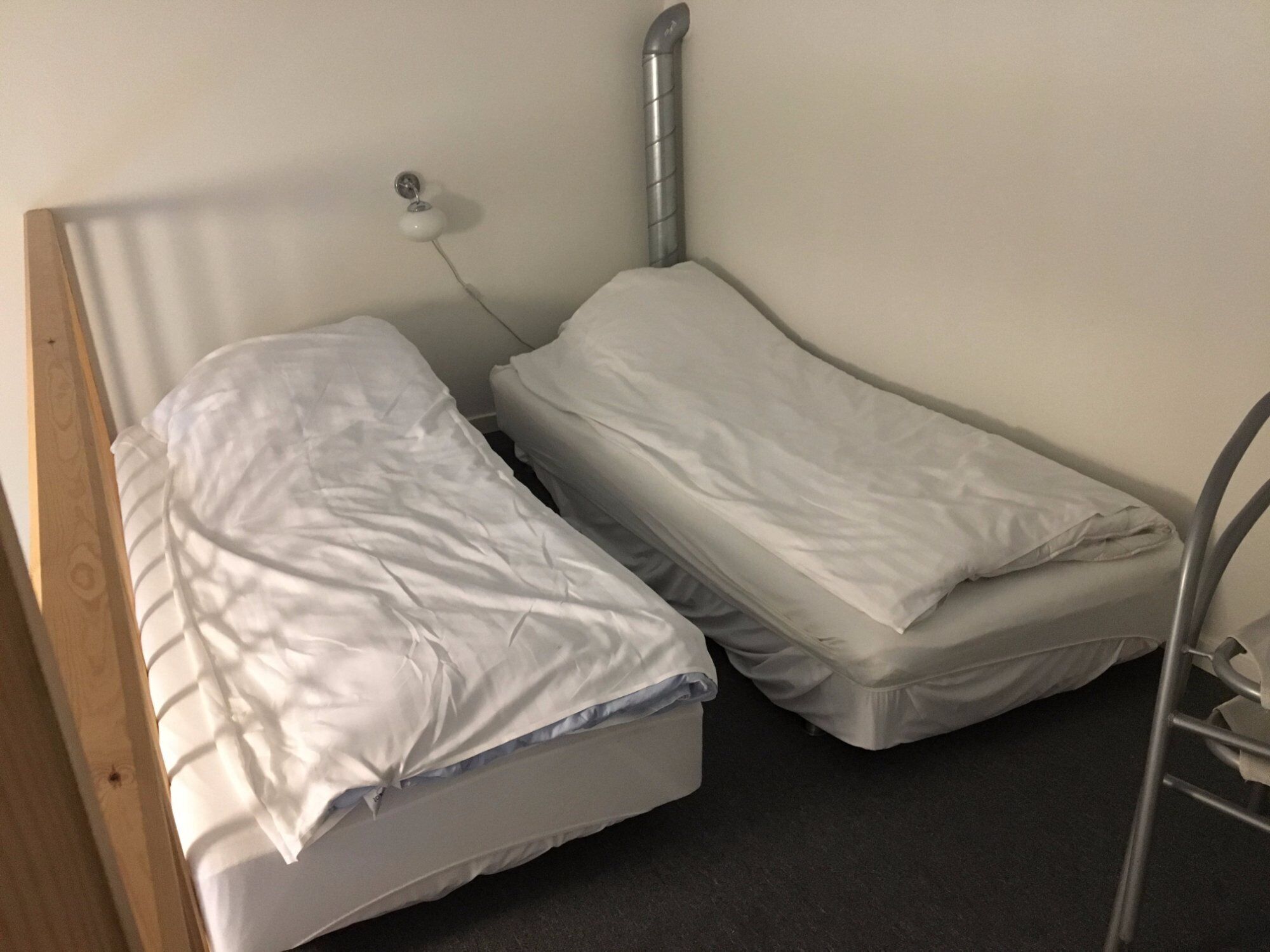A small, single-bed room with a wooden headboard and a metal ladder.
