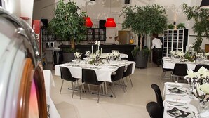 Un restaurante con varias mesas dispuestas para comer, con manteles blancos y sillas negras.