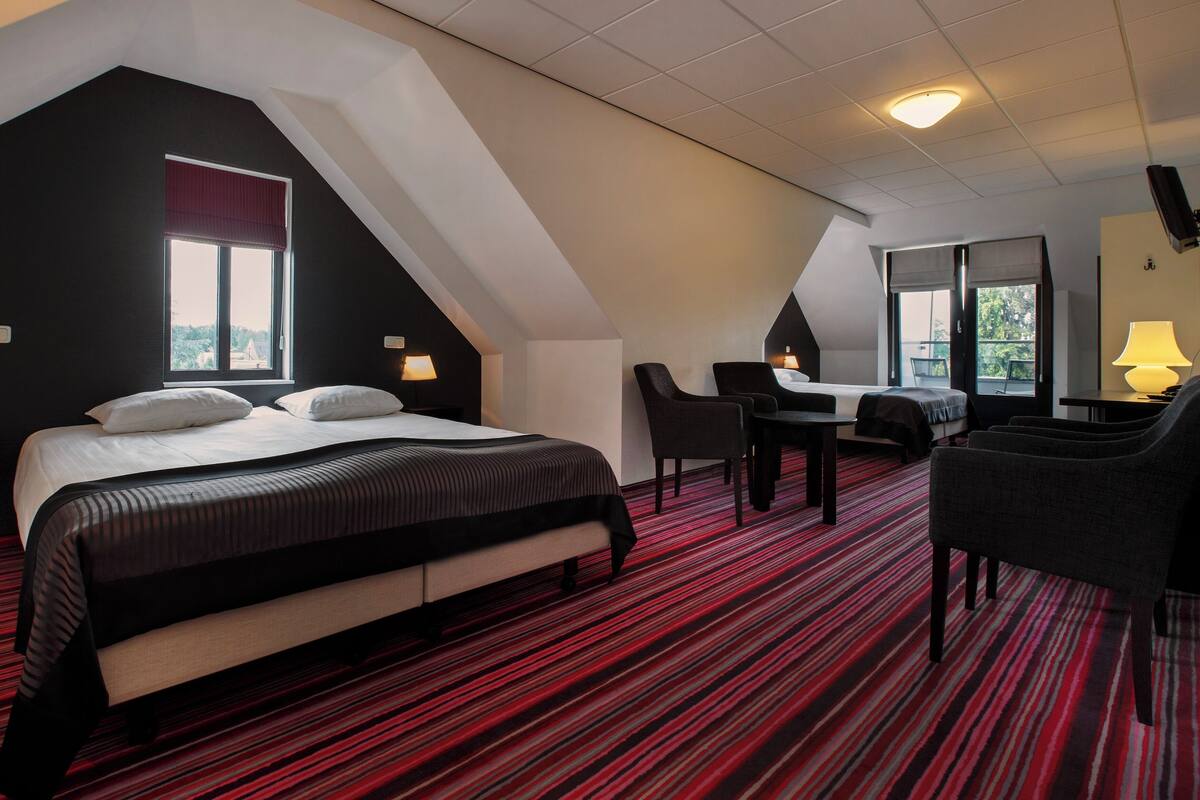 A hotel room with a bed, a desk, a chair, and a view of the outdoors.