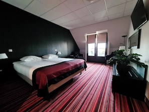 A hotel room with a bed, a desk, a chair, a TV, and a window. - Hotel de Schout (Denekamp)