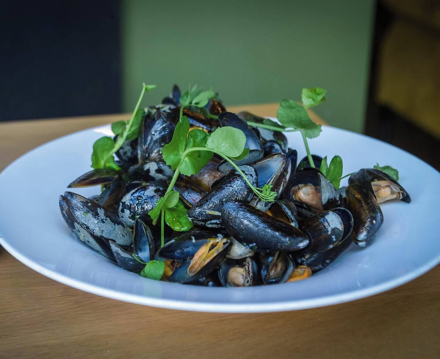 A plate of mussels garnished with green leaves.