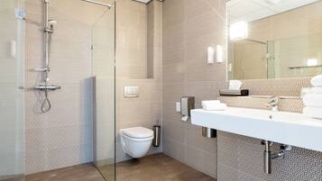 Un bany modern amb parets amb dibuixos, un box de dutxa de vidre, un vàter i un lavabo amb mirall.